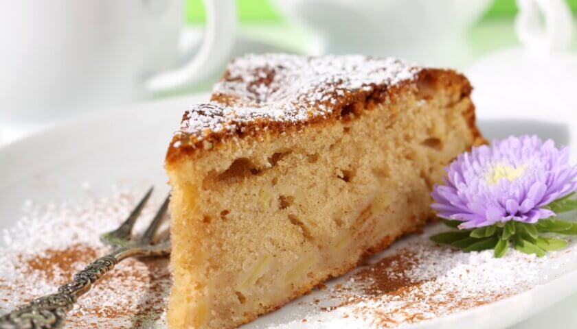haselnuss-apfelkuchen mit staubzucker und blumendeko auf teller