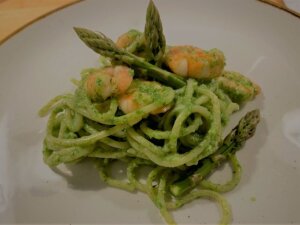 spaghetti mit spargel-spinatpesto und garnelen auf teller angerichtet