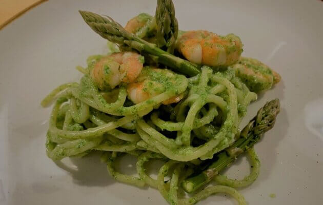 spaghetti mit spargel-spinatpesto und garnelen auf teller angerichtet