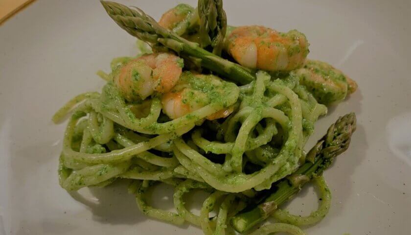 spaghetti mit spargel-spinatpesto und garnelen auf teller angerichtet